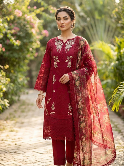 Woman wearing a red embroidered traditional outfit with a dupatta in a garden setting